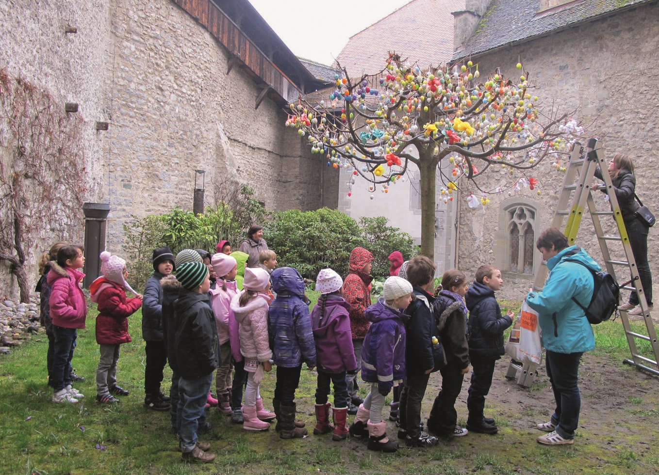 Kinder stehen vor einem Osterbaum