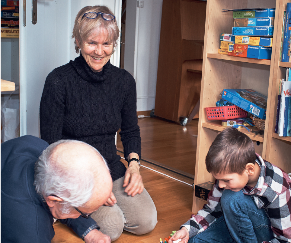 Grossmutter und Grossvater spielen mit ihrem Enkel in seinem Zimmer