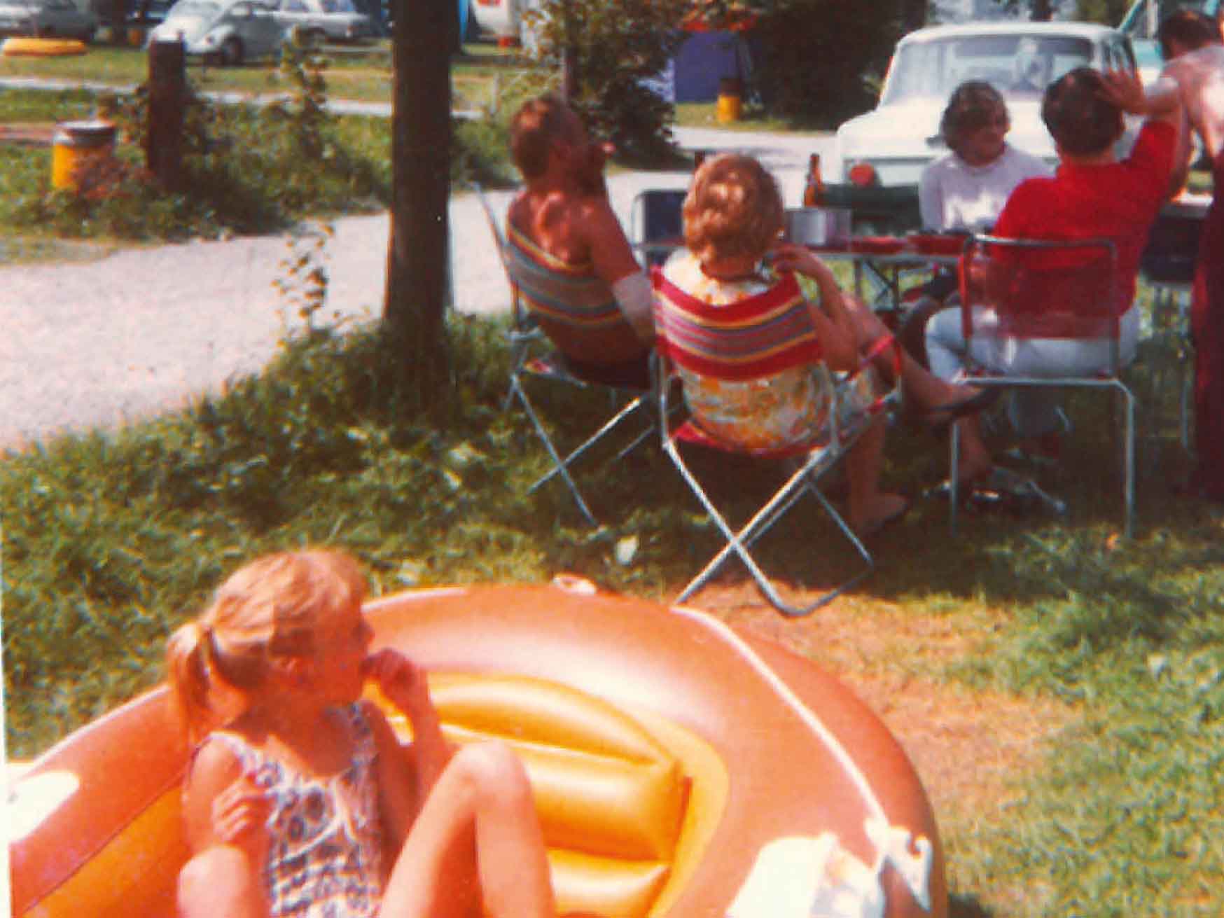 Ein Mädchen sitzt in einem Gummiboot und die Erwachsenen sitzen am Tisch