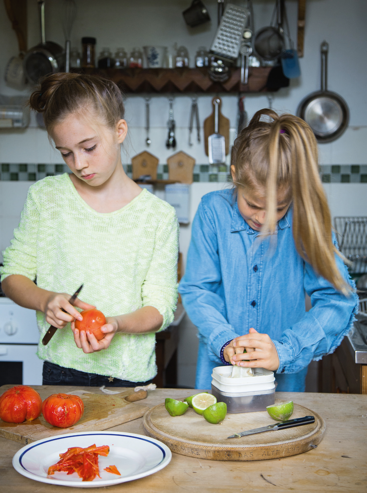 Zwei Mädchen rüsten Tomaten und Limetten