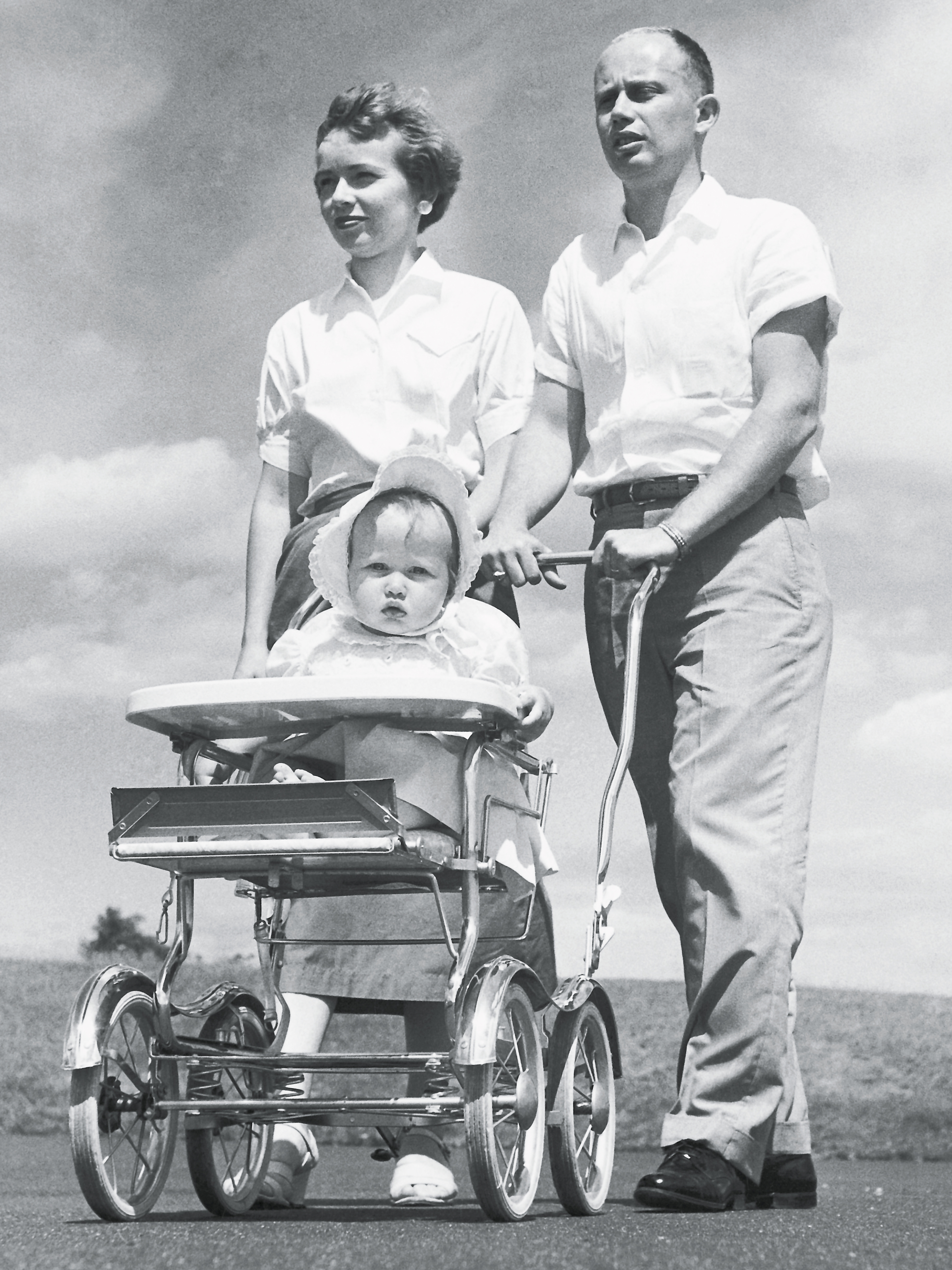 Mutter und Vater am Spatzieren mit Kleinkind im Kinderwagen