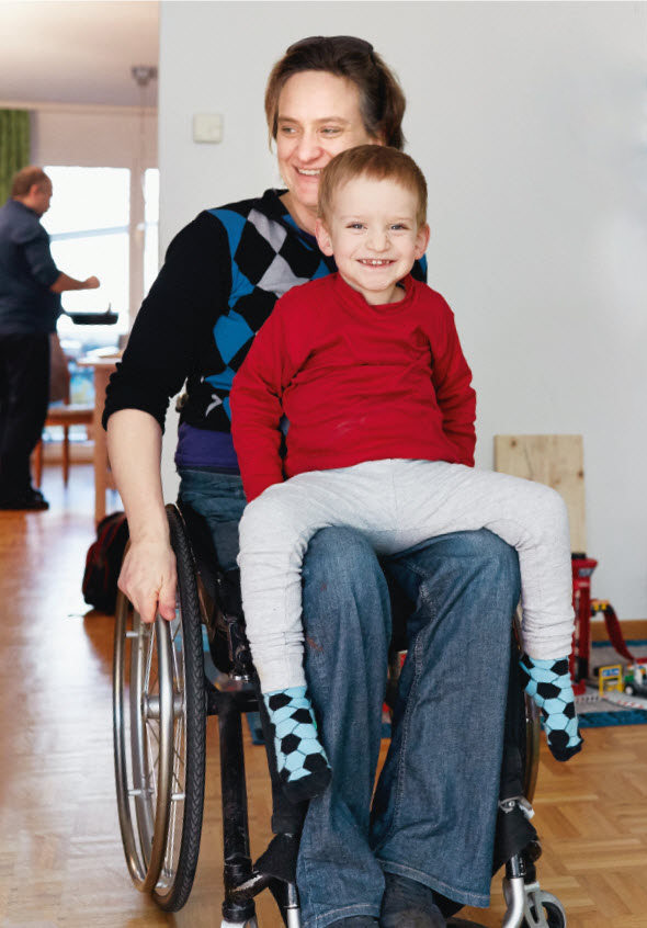 Junge bei Mutter auf dem Schoss im Rollstuhl