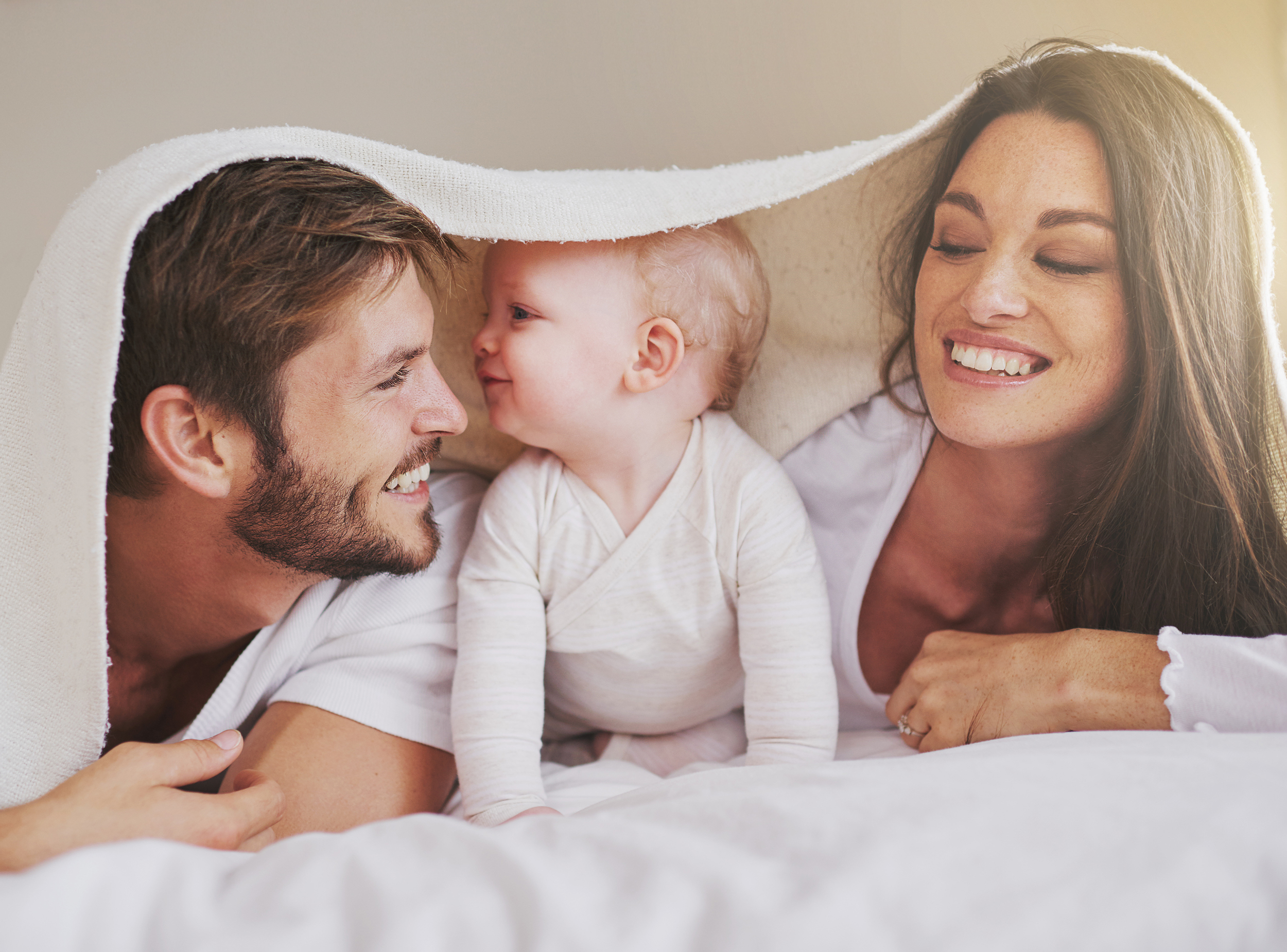 Baby unter Decke mit Eltern