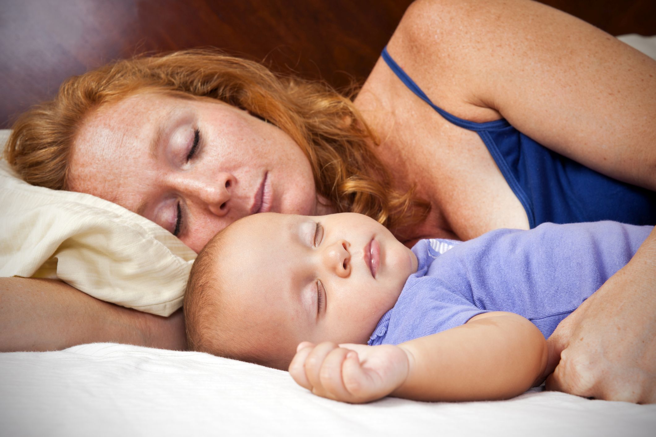 Eine Mutter schläft mit ihrem Baby im Elternbett