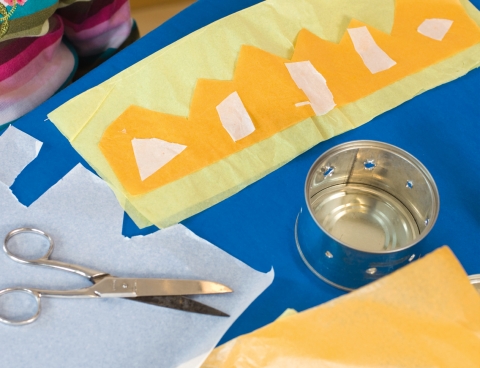 Aus Seidenpapier Verzierungen schneiden und diese mit Leimstift auf die Manschette kleben.