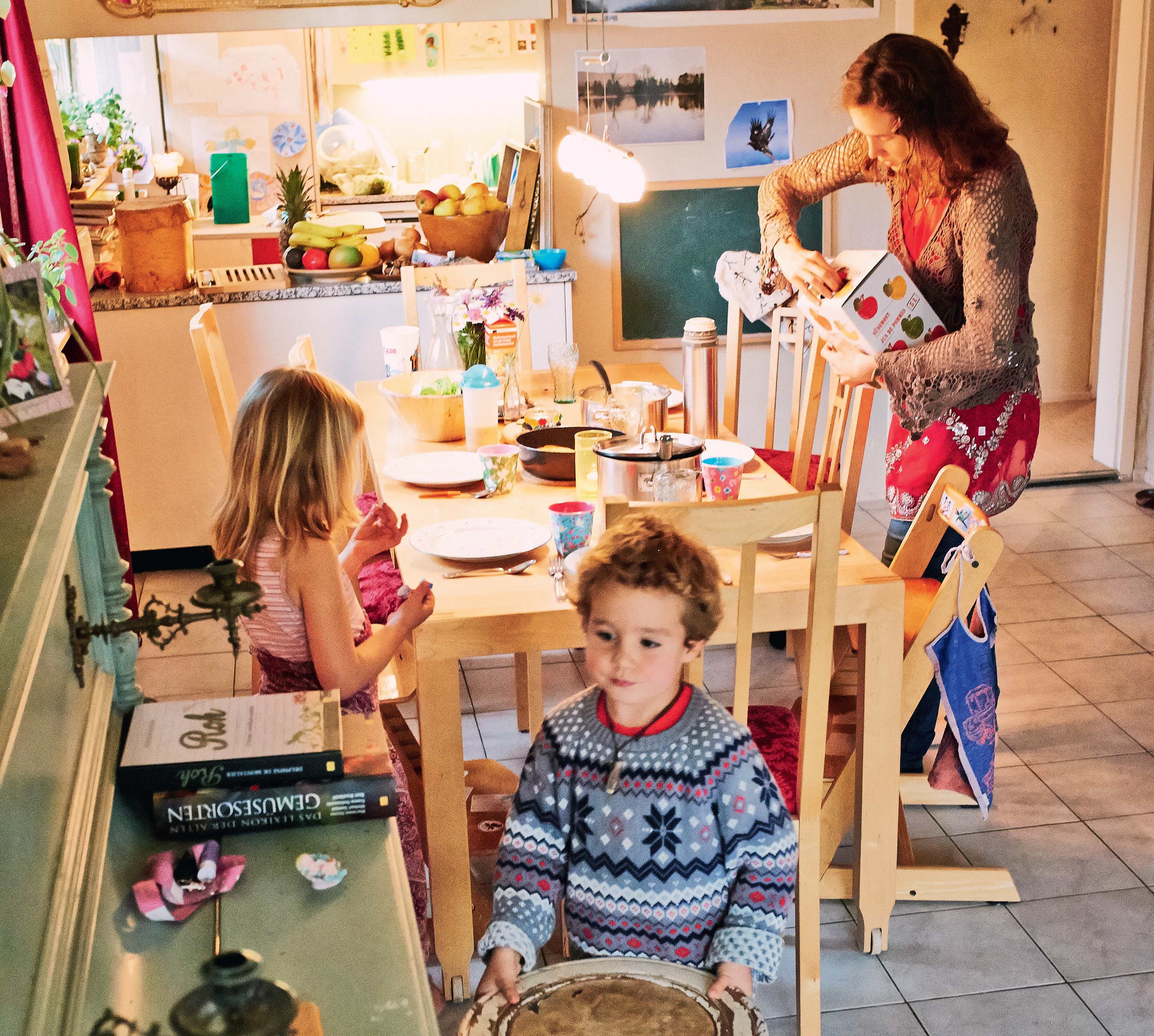 Mutter und zwei Kinder stehen in der Küche und der Tisch ist gedeckt