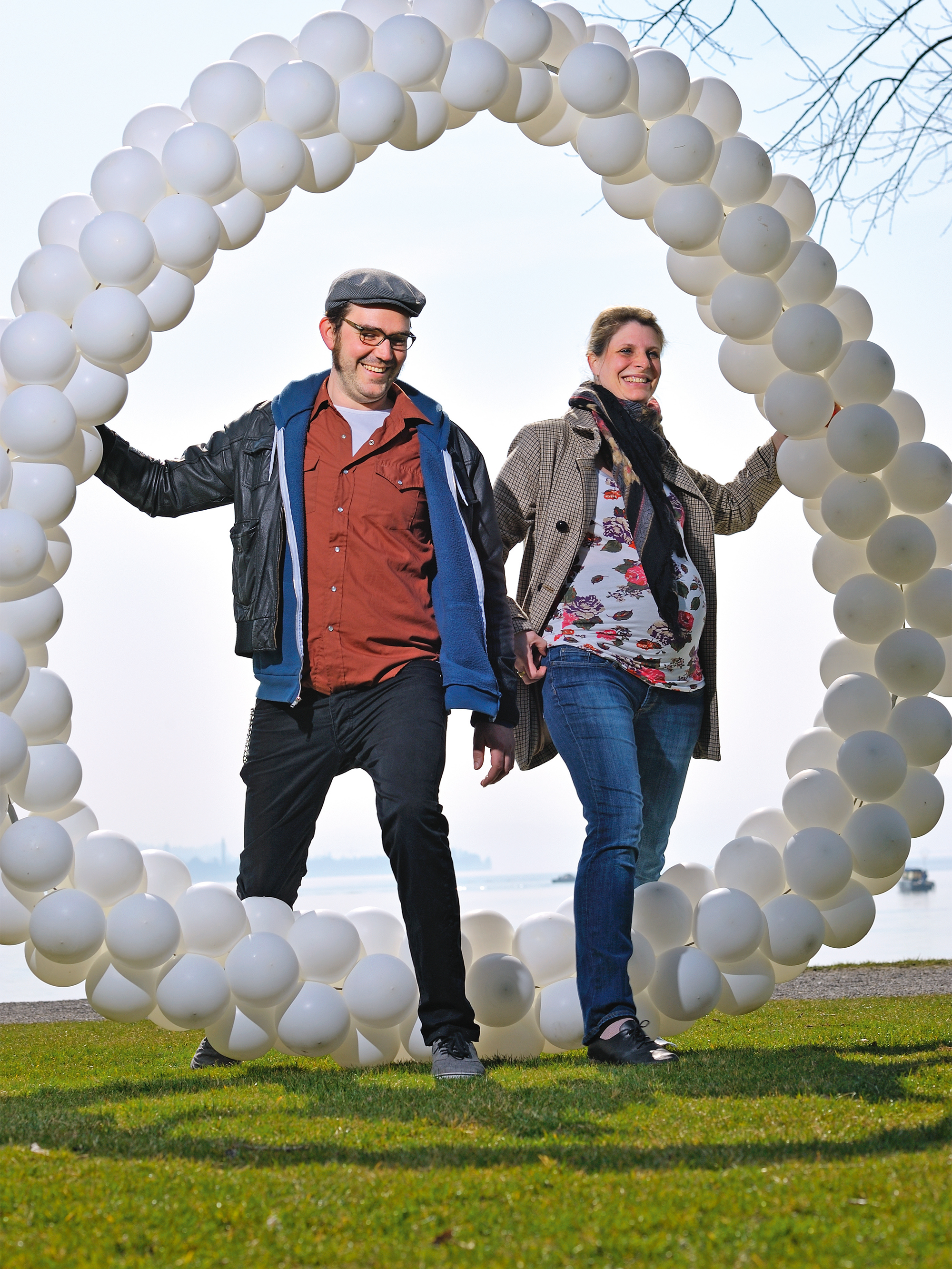 Mann und Frau laufen durch ein Kreis aus Luftballons