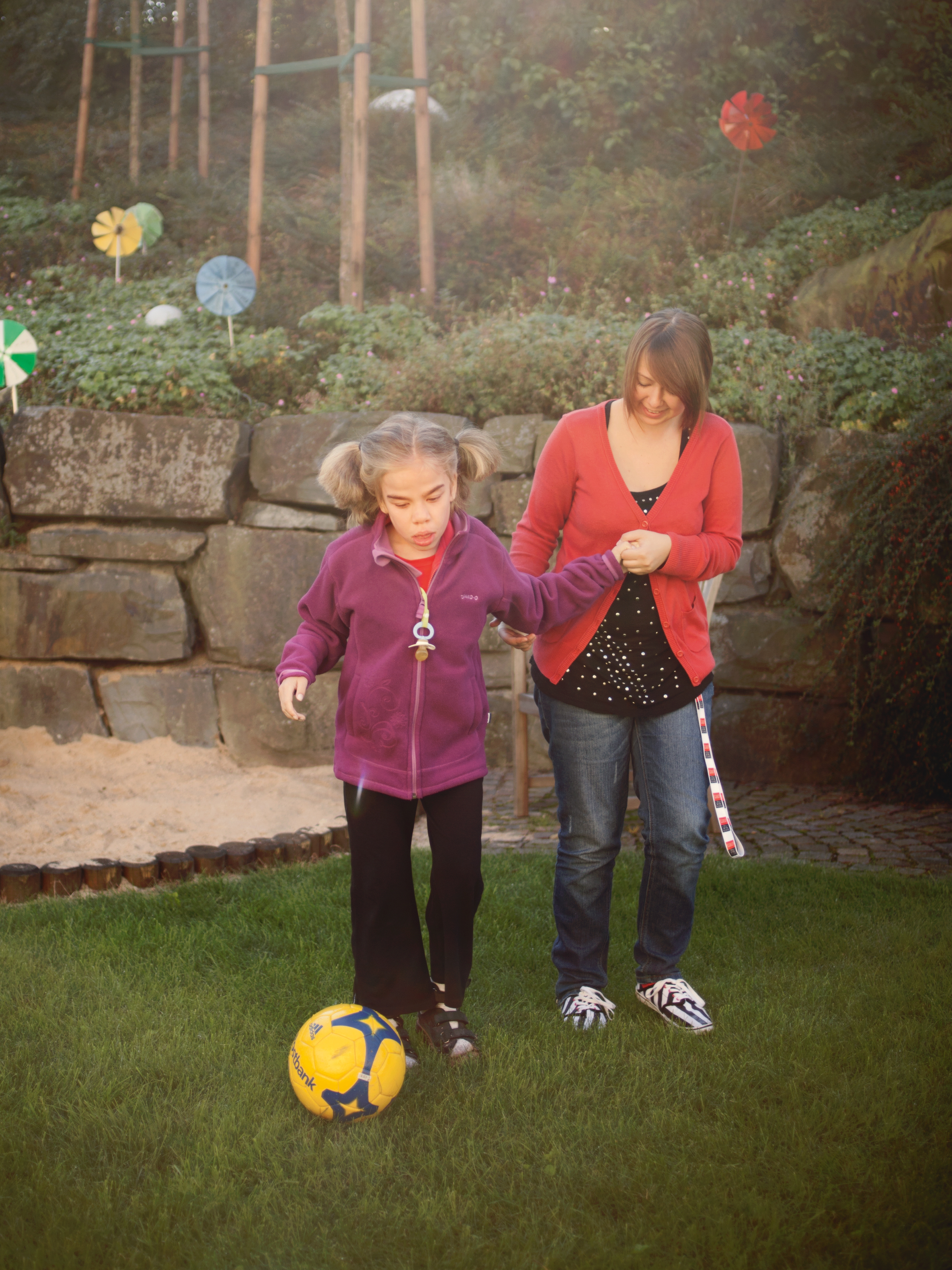 Schwerkrankes Kind spielt mit Mutter Fussball