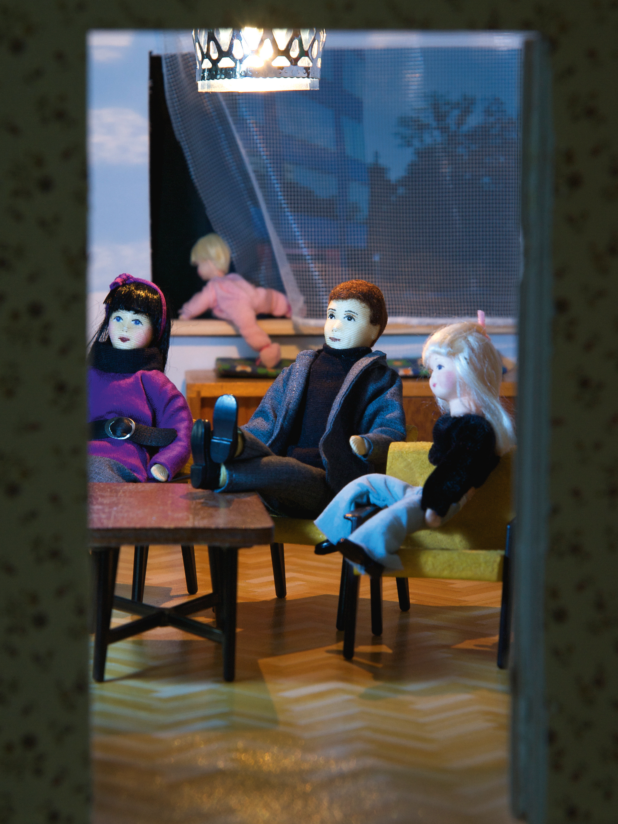 Diorama: Mutter, Vater und erstes Kind hocken auf dem Sofa während das Kleinkind aus dem Fenster klettert