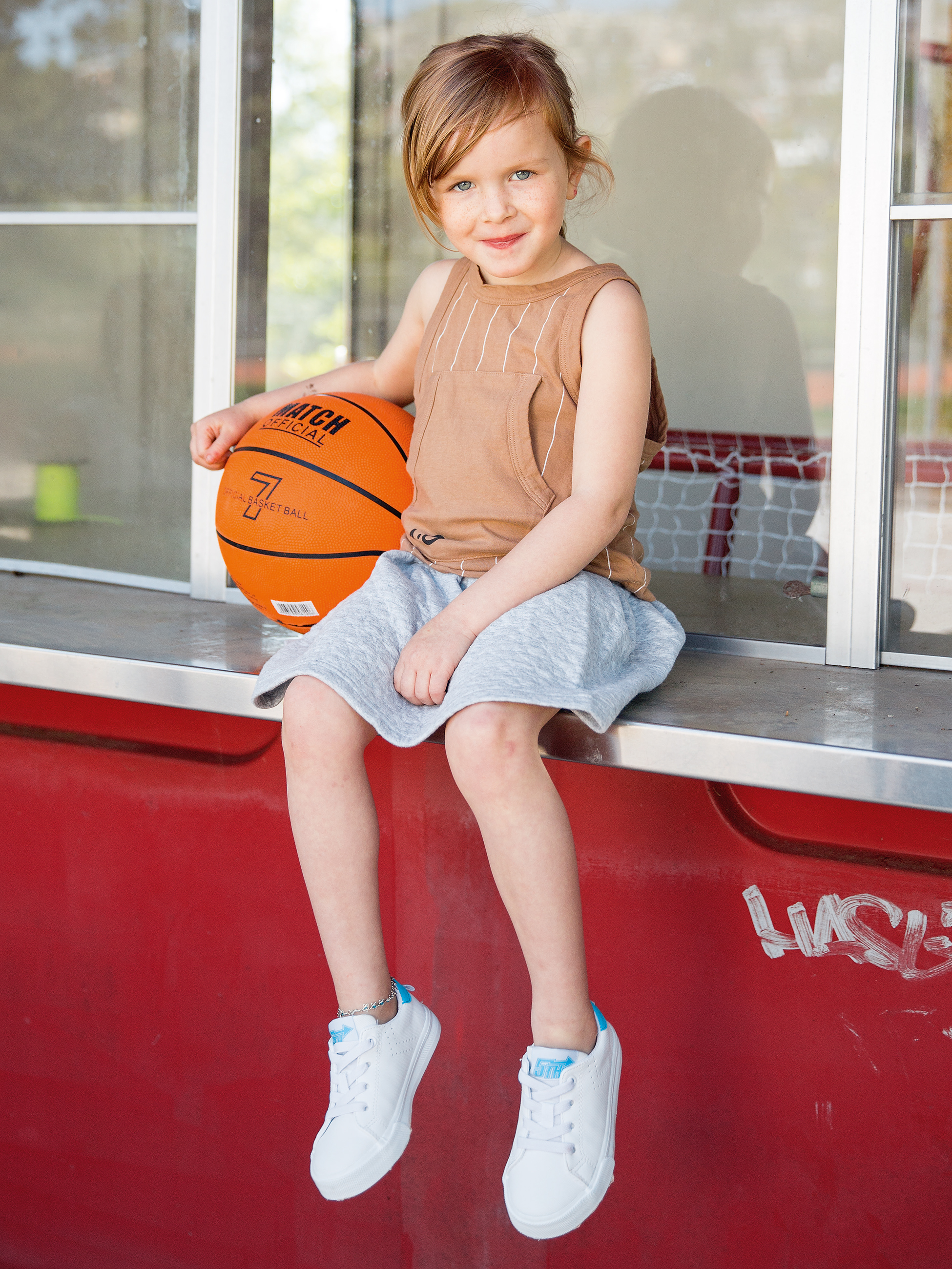 Mädchen sitzt auf einer Theke mit Basketball