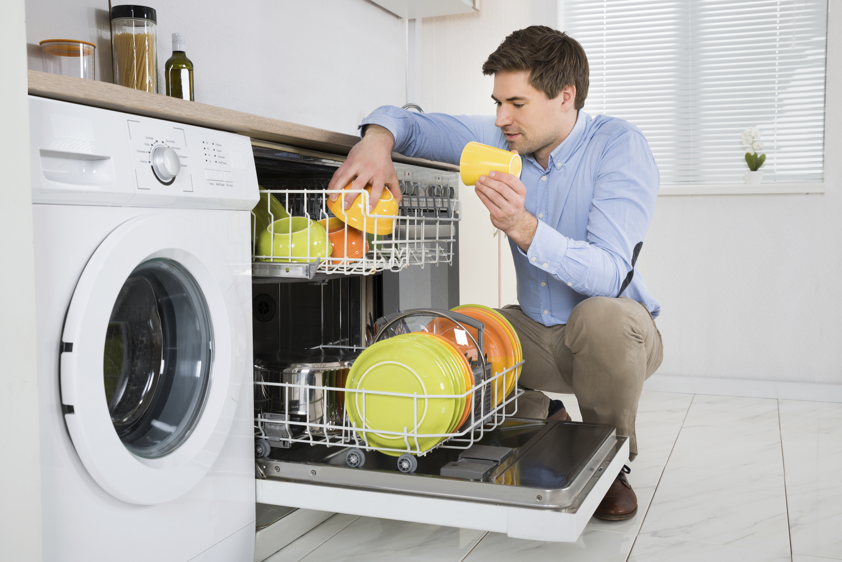 Mann beim Ausräumen der Geschirrspühlmaschine