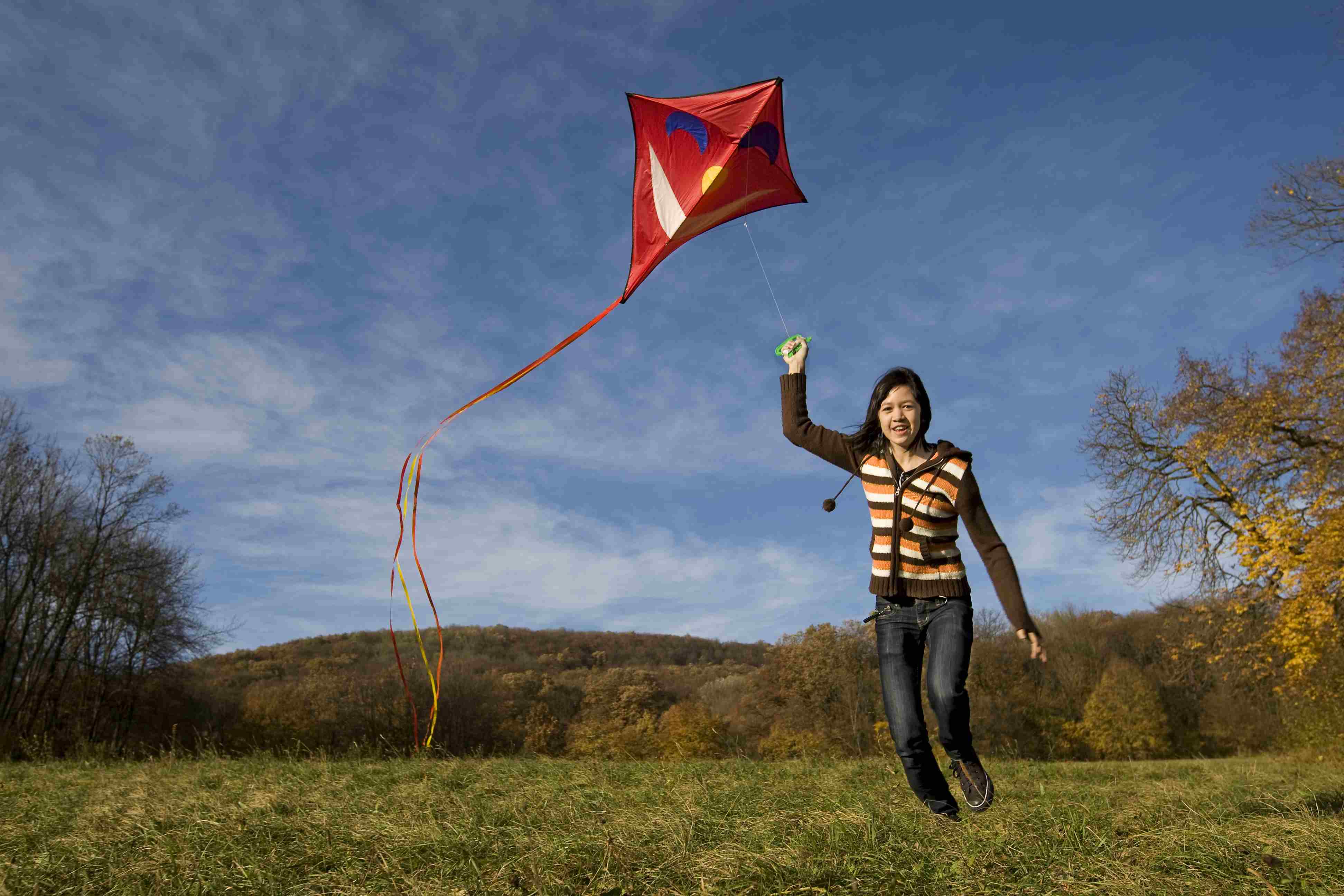 Mädchen auf Anhöhe mit Drachen im Herbst