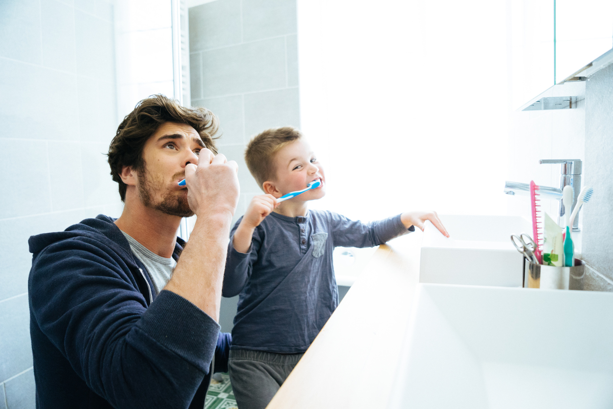 Vater putzt Zähne mit Kind