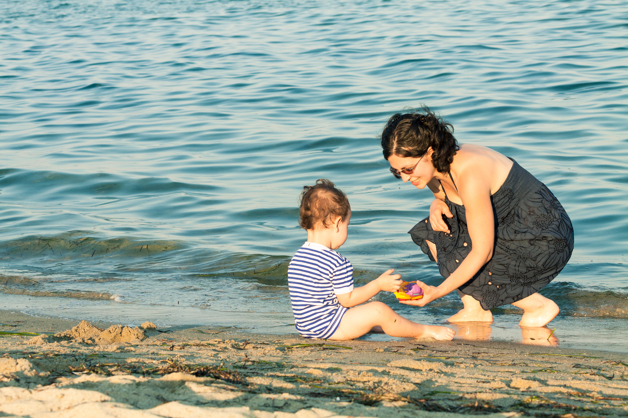 Mutter und Kleinkind spielen am Strand