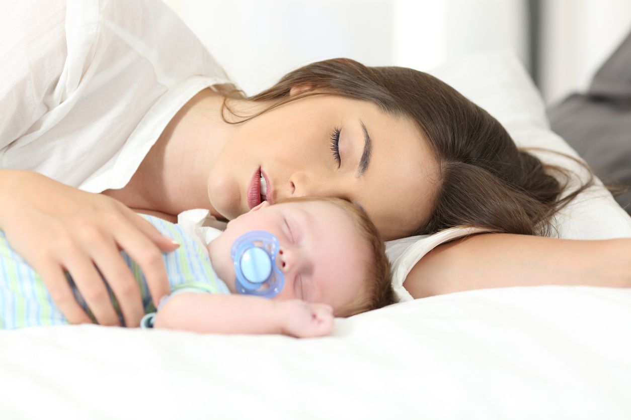 Tiefschlafende Mama mit Baby im Bett