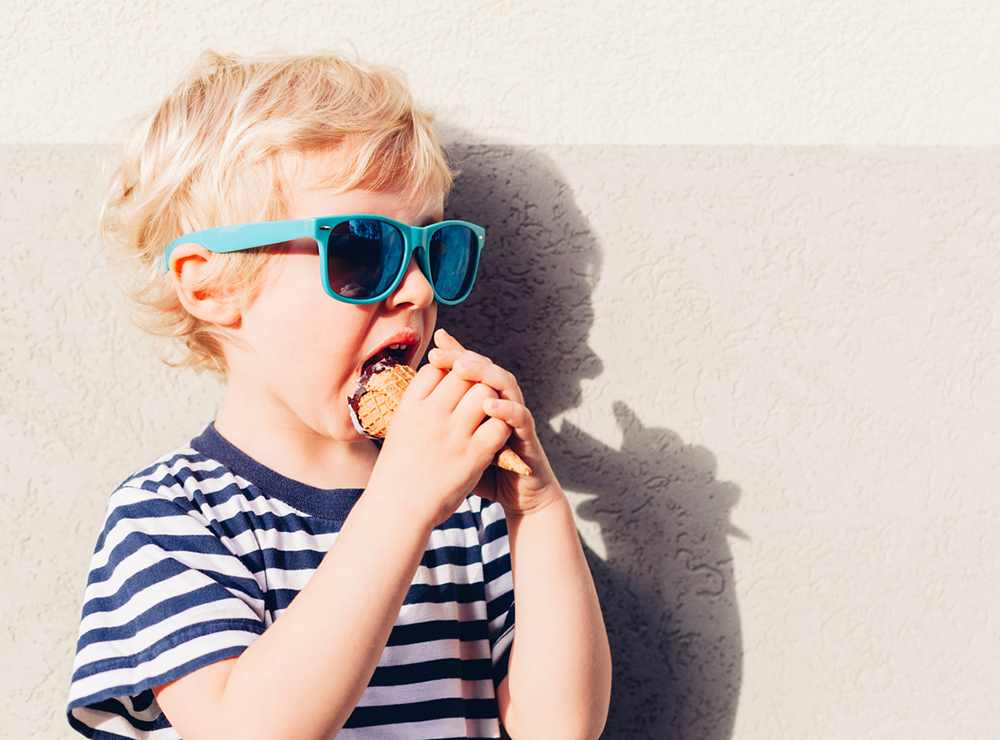 Blonder Junge mit Sonnenbrille und Glace