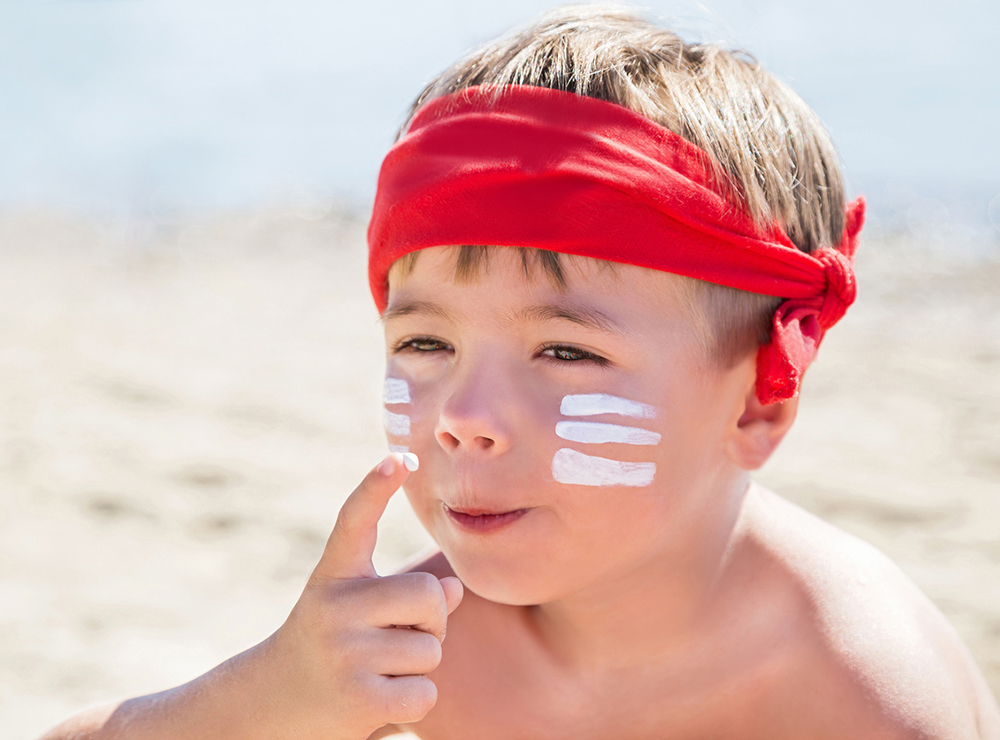 Kind am Strand mit Sonnencreme im Gesicht