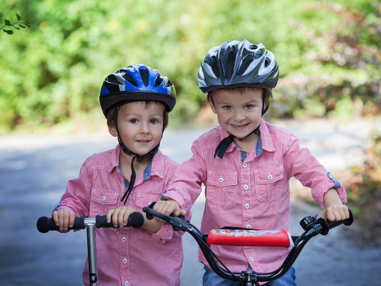 Zwei Junge auf Velo und Scooter mit Helmen
