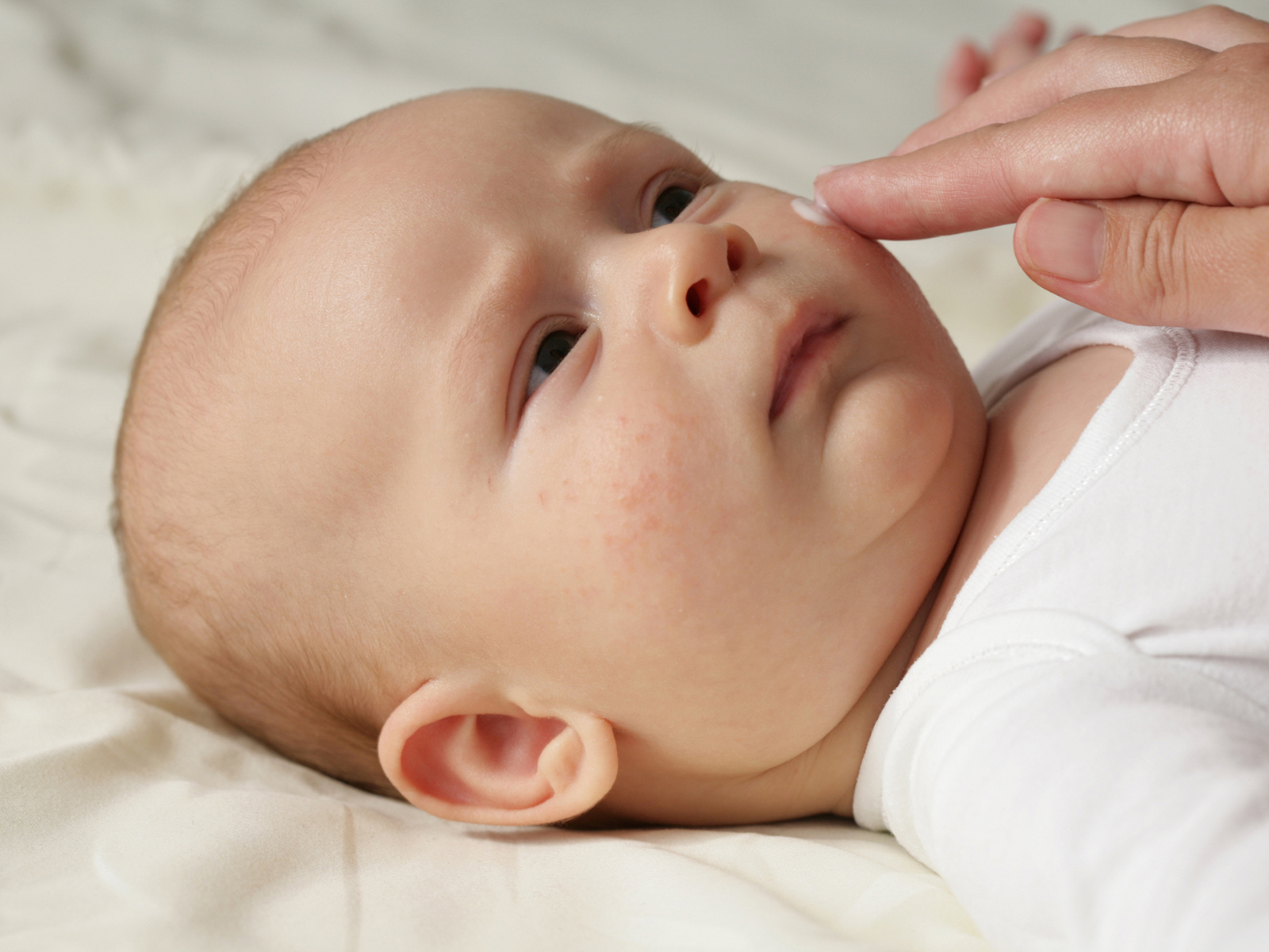 Baby wird im Gesicht mit Creme eingerieben