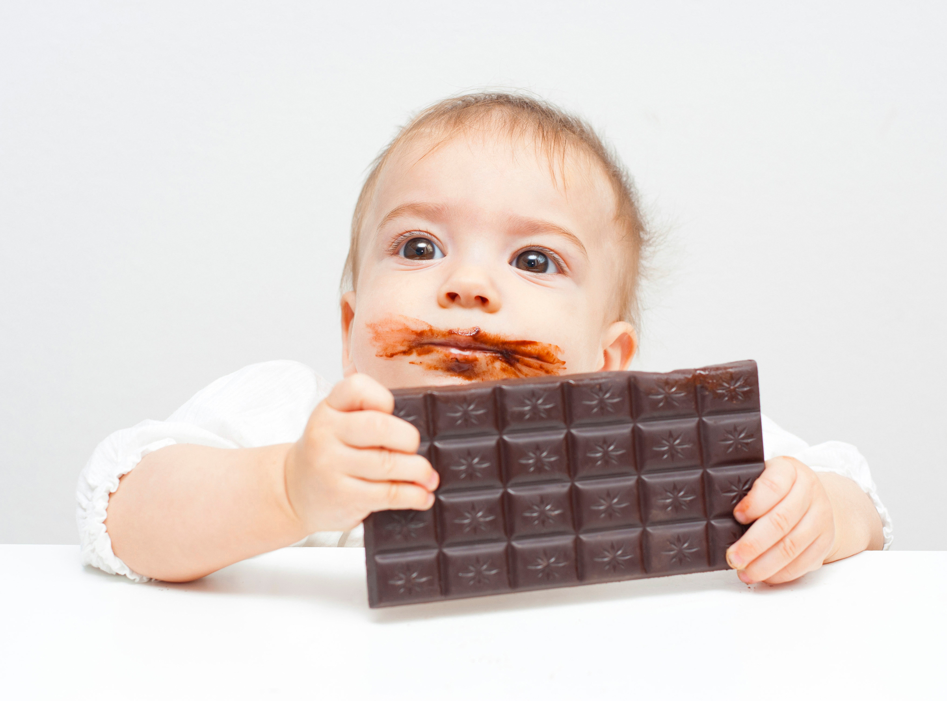 Baby mit Schoggitafel in der Hand