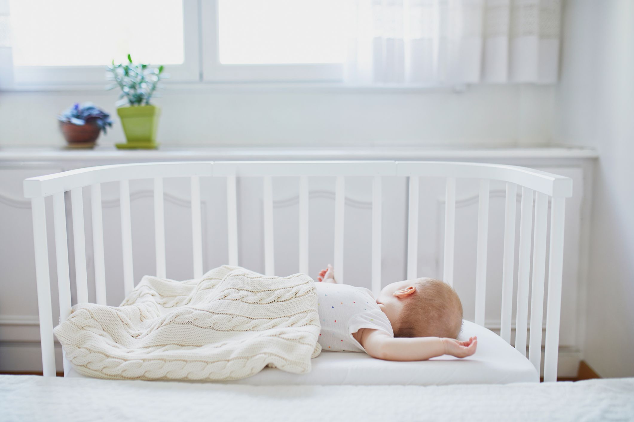 Ein Baby schläft im Beistellbett direkt am Bett der Eltern