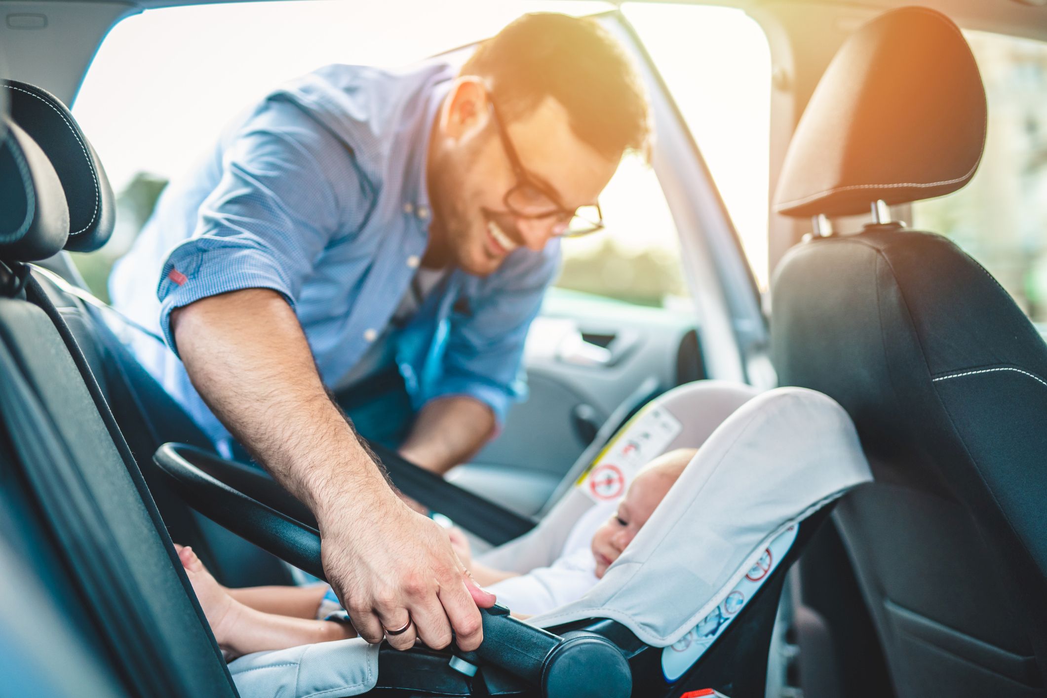 Ein Vater befestigt sein Baby im rückwärts gerichteten Autositz.