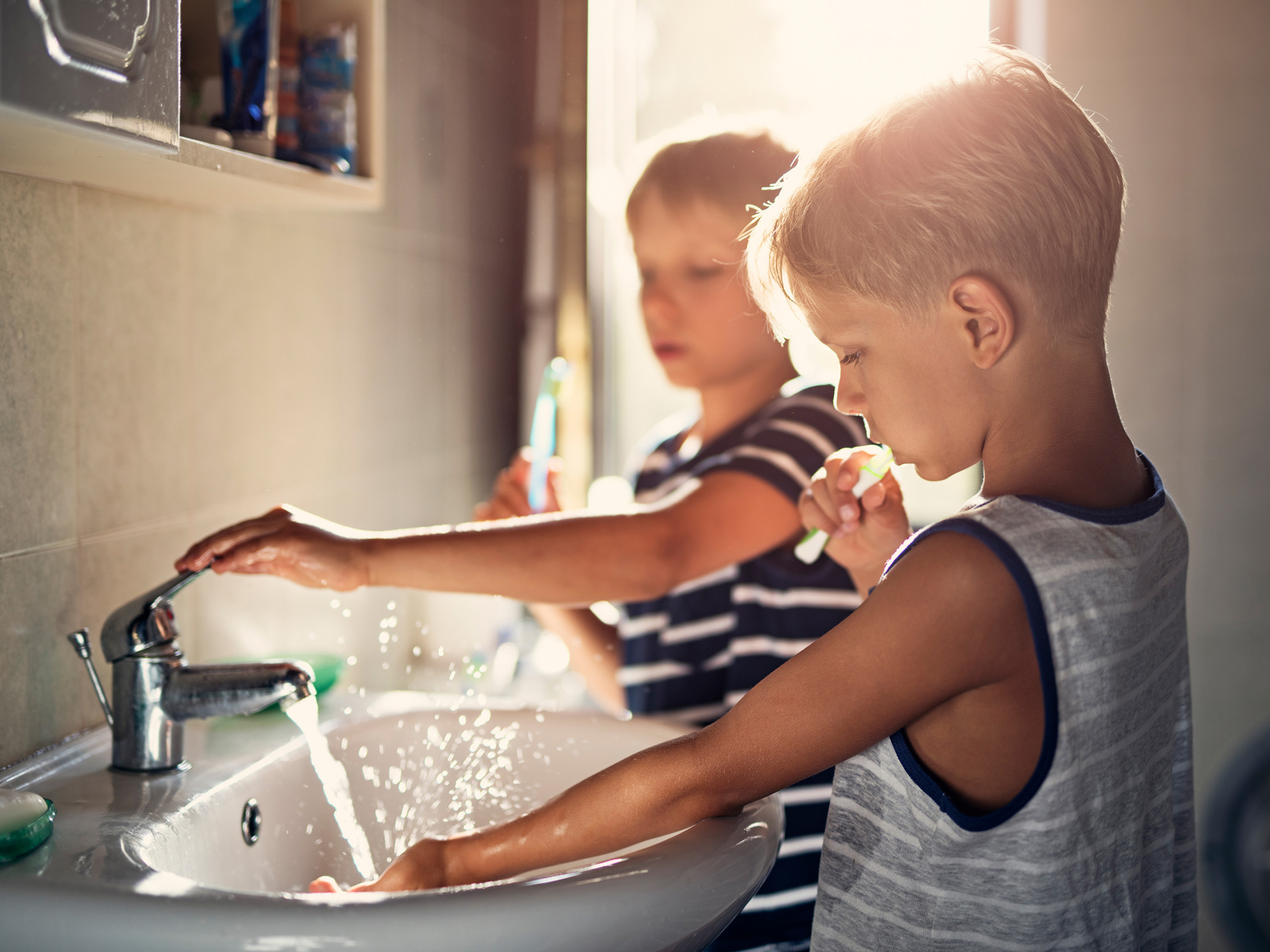 Zwei Kinder putzen sich mit einer Kinderzahnbürste die Zähne.