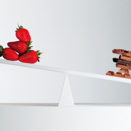 Waage mit Erdbeeren auf einer Seite und Schokolade auf der andere