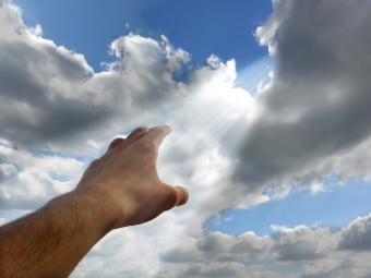 Hand reicht für das Licht dass vom Himmel kommt