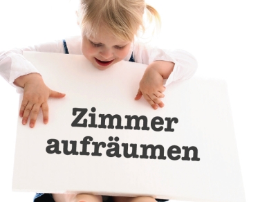 Kind hält Schild wo steht «Zimmer aufräumen»