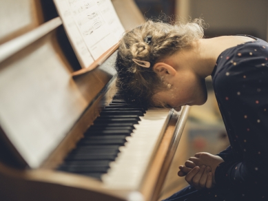 Mädchen legt Kopf aufs Klavier