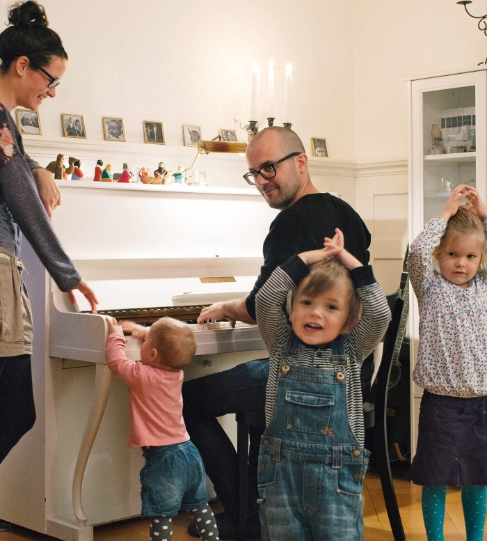 Vater spielt Klavier, Familie versammelt sich rundherum