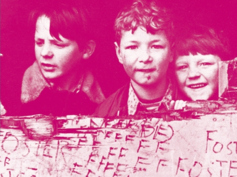 Foto aus den 1970er-Jahren: Drei Jungs schauen hinter einem Transparent hervor