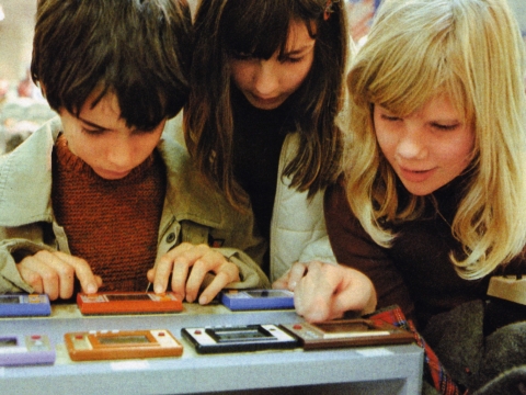 Drei Kinder spielen mit den ersten Nintendo-Taschencomputer-Spielen