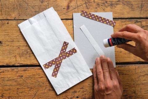 Den Papierstreifen übers Kreuz zu einem Stern anordnen und auf die Tüte kleben.