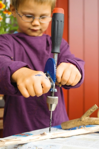 In einen langen Ast mit dem Handbohrer Löcher im Abstand von ca. 3 cm bohren.