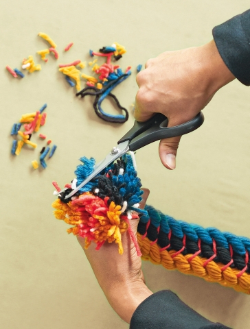 Am Schluss die abstehenden Wollfäden mit einer Schere zu einem Pompom frisieren.