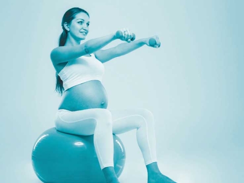 Eine schwangere Frau sitzt auf einem Gymnasikball