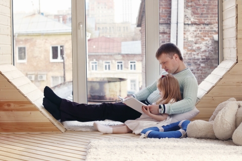 Vater und Tochter schauen ein Buch an