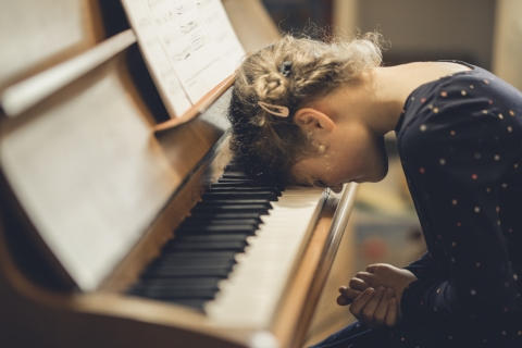 Mädchen legt Kopf aufs Klavier