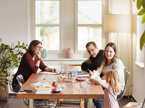 Die Doula sitzt mit dem Ehepaar, das ein Kind erwartet zum Vorgespräch am Tisch