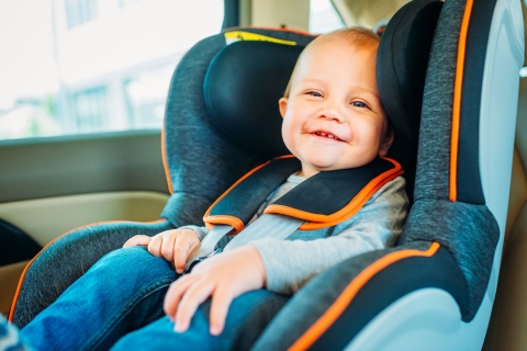 Ein Kleinkind sitzt zufrieden im Autositz. 